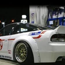 back side of a white car with some gold rims and a few decals